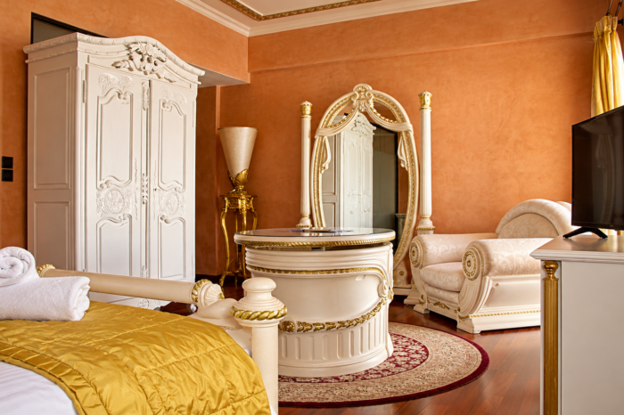 Comfort Junior Suite featuring luxury white and gold baroque furniture and terracotta walls at Anastazia Luxury Suites & Spa