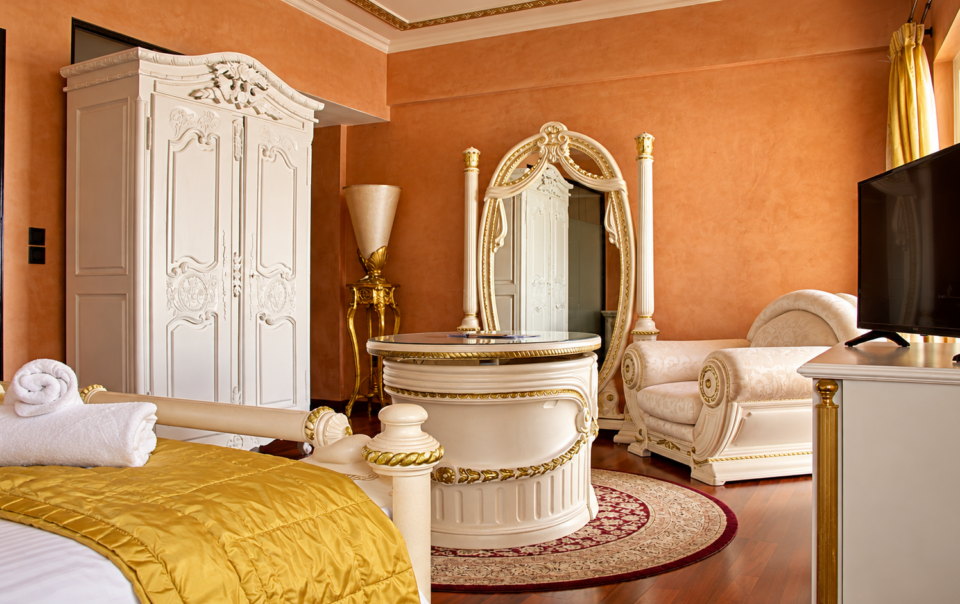 Comfort Junior Suite featuring luxury white and gold baroque furniture and terracotta walls at Anastazia Luxury Suites & Spa