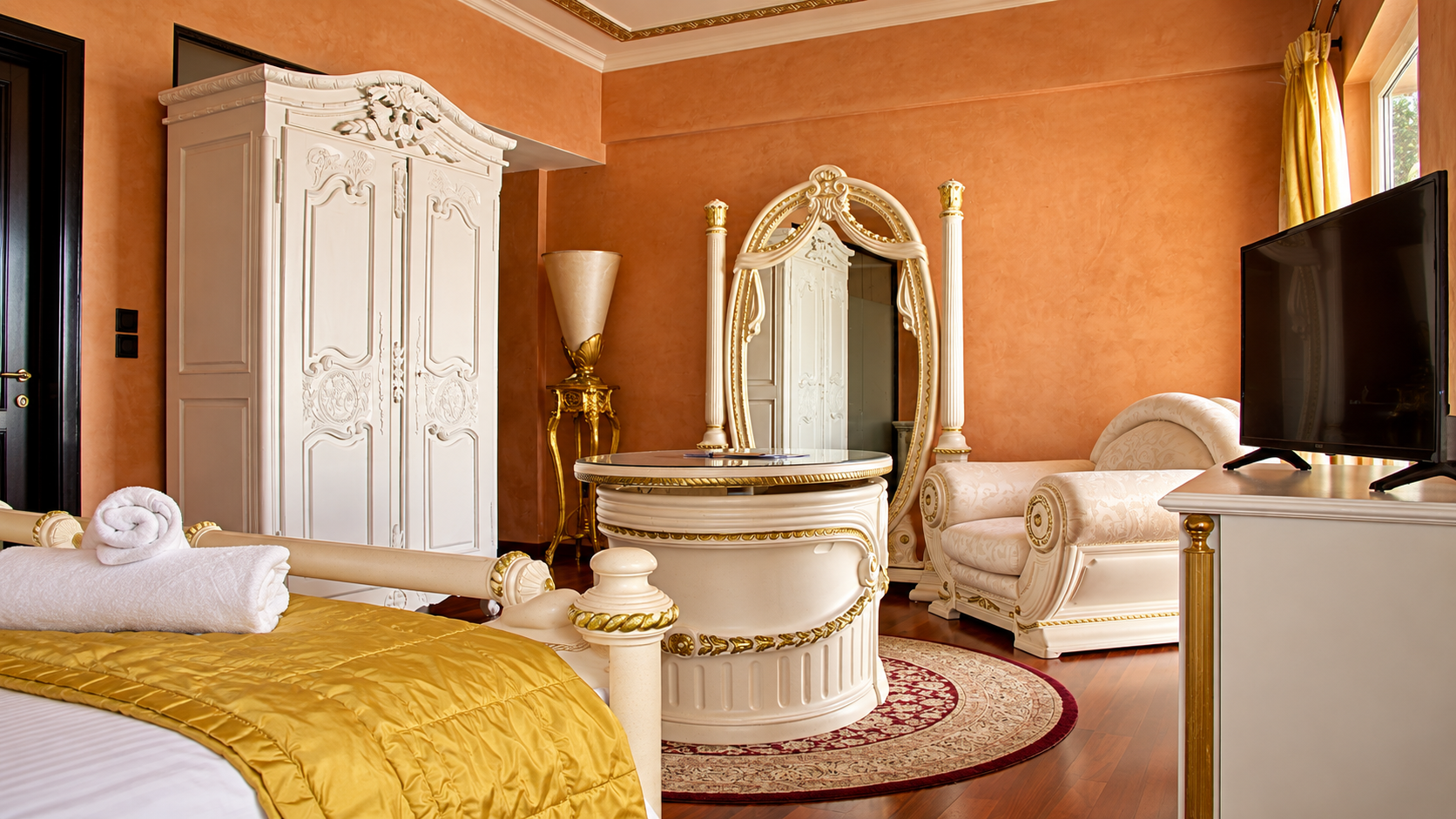 Comfort Junior Suite featuring luxury white and gold baroque furniture and terracotta walls at Anastazia Luxury Suites & Spa