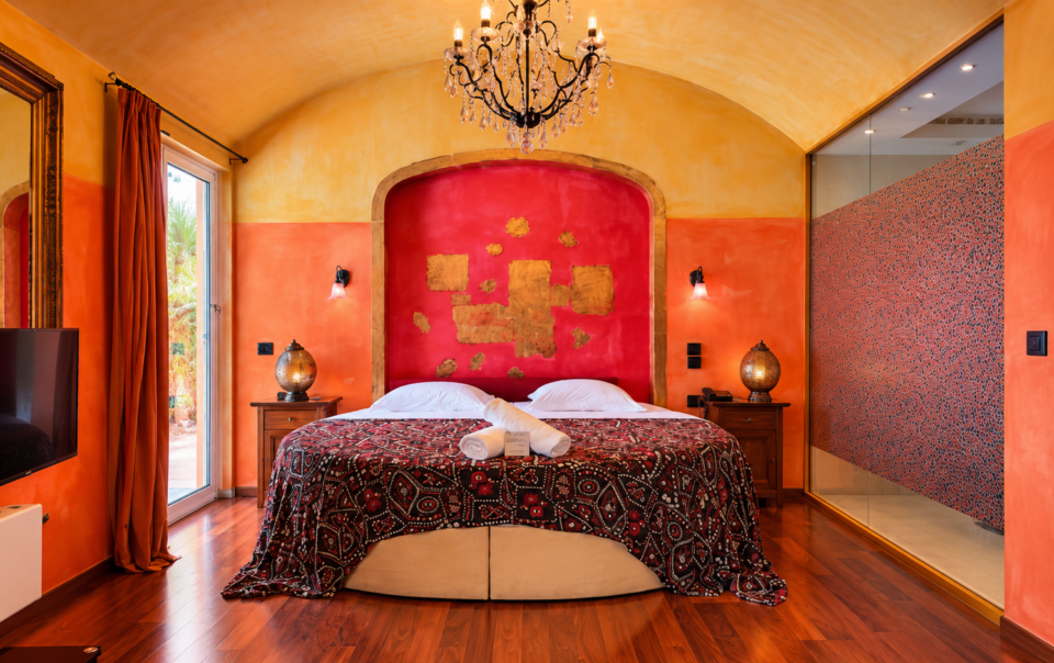 Executive Suite bedroom featuring a luxurious round bed and a crystal chandelier at Anastazia Luxury Suites & Spa
