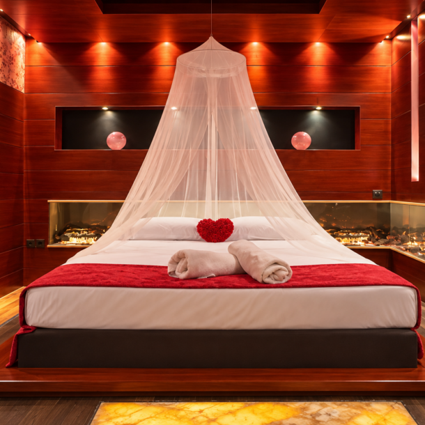 Anastazia Luxury Suites Deluxe Suite featuring a romantic canopy platform bed, red ambient lighting, mahogany wood panels, and a built-in panoramic fireplace in Drosia